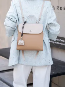 Dettaglio di mini zaino bicolore in pelle con chiusura a torsione e grazioso ciondolo chic.