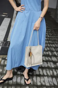 Leather tote bag detail, minimalist commuter shoulder bag with stylish wooden bead charm.