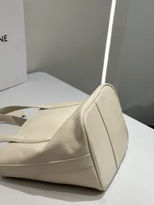 Close-up detail of premium off-white leather tote bag, showing fine texture and fine stitching.
