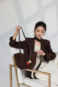 Detail shot of stylish brown leather tote bag with cute charm, elegant daily fashion accessory.