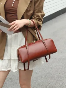 Brown leather cylinder shoulder bag, stylish bowling bag with metal buckles for women.