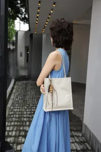 Genuine leather simple versatile tote bag featuring wooden bead pendant for daily commuting.