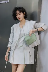 Close-up detail view of the light green leather mini crossbody bag in a stylish lifestyle scene.