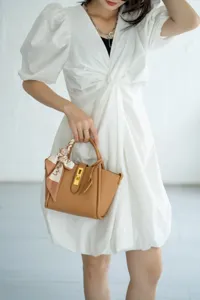 Vista dettagliata della elegante borsa da donna in pelle marrone con serratura e foulard di seta.