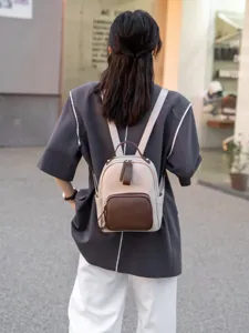 Vista dettagliata dell'elegante zaino in pelle bicolore indossato da una modella all'aperto.