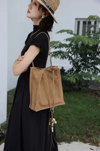 Detailed view of brown suede tote bag worn by model, simple commuter shoulder bag style.