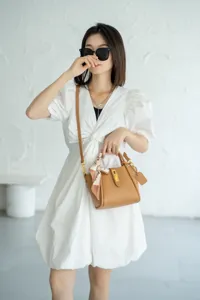 Dettaglio di una elegante borsa da donna in pelle con lucchetto e foulard in studio.