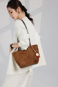Close-up detail of brown suede leather tote shoulder bag with cute strawberry flower charm.