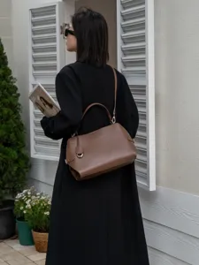 Detail view showing the elegant brown leather shoulder bag in a stylish outdoor setting.