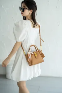 Vista dettagliata di una elegante borsa a tracolla in pelle marrone con manico, indossata.
