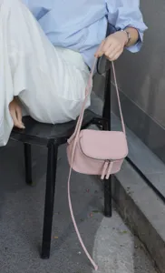 Detail view of pink leather mini crossbody bag with zipper and slim strap closeup shot