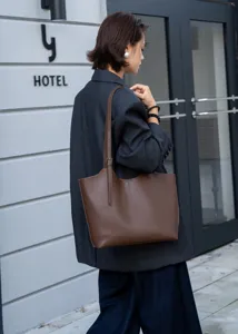 Brown leather tote bag detail showing minimalist commuter style and large capacity daily use.