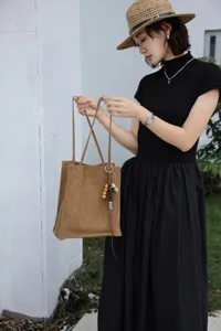 Elegant brown leather tote bag detail, featuring beaded charms, perfect for daily commute.