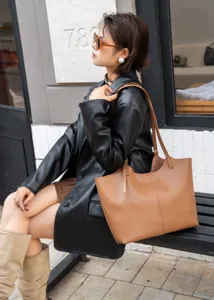 Close-up of stylish brown leather tote bag worn by model outdoors, commuter design.