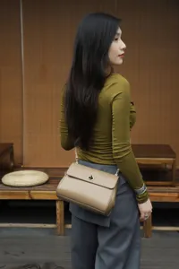 Detailed view of a stylish leather shoulder bag in chic khaki with metal lock closure.
