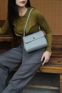 Detail shot of a stylish grey leather women shoulder bag with metal lock for daily commute.