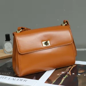 Detailed view of a vintage brown leather shoulder bag with metallic lock closure and strap.