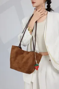 Brown suede tote shoulder bag detail showing genuine leather texture and cute strawberry charm.