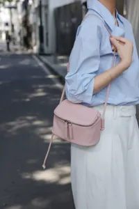 Pink leather mini crossbody bag detail view showcasing smooth texture and zipper design.