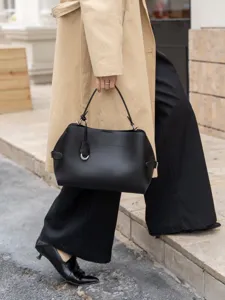 Detail shot of the black leather shoulder handbag in an urban street setting, minimalist.