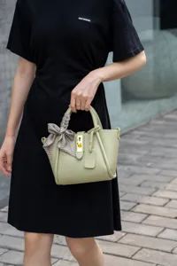 Elegante borsa a secchiello in pelle da donna, borsa verde chiaro con manico e foulard.