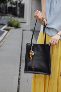 Detailed view of the genuine leather black tote bag with unique wooden bead charm.