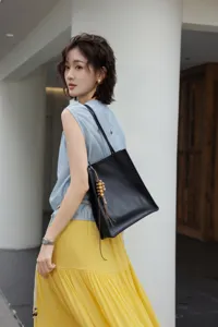 Detailed view of a minimalist black genuine leather tote shoulder bag with beaded charm.