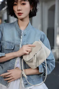 Close-up of a minimalist beige leather crossbody bag featuring a unique geometric panel design.