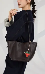 Close-up detail view of the brown genuine leather bucket bag with cute strawberry charm.