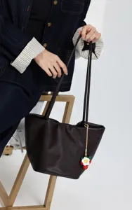 Genuine leather tote bag with bucket design, slim shoulder straps and cute strawberry charm.