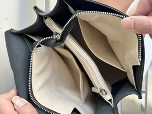 Vista dettagliata dell'interno di una borsa nera con scomparti multipli con zip.