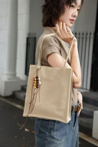 Minimalist genuine leather tote bag detail, stylish commuter shoulder bag with wooden beads.