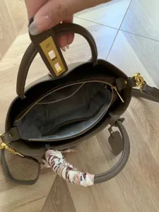 Elegante borsa a mano da donna in pelle marrone con chiusura in metallo e foulard chic.