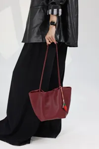Detailed view of the burgundy genuine leather bucket tote bag with cute strawberry charm.