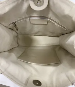 Detailed interior view of a cream leather tote bag featuring zipper pocket and lining.