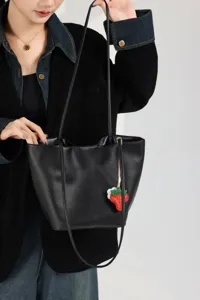 Black leather tote bag detail showing premium cowhide texture, large capacity bucket design.