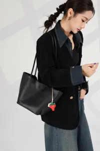 Detail shot of black leather shoulder tote bag worn by model, showing large capacity daily wear.
