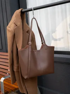 Vue détaillée d'un sac cabas en cuir marron avec bandoulière et boucle métallique au crochet.