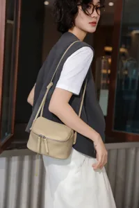 Detail view of the mini beige leather crossbody bag worn by model, showcasing fine texture.