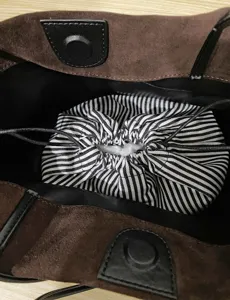 Leather bucket bag interior detail showing stylish striped inner pouch and soft suede texture.