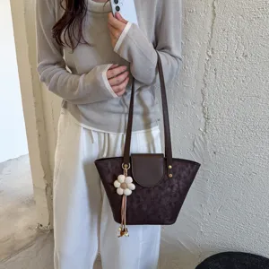 Close-up detail of a dark brown shoulder tote bag with cute flower charm for stylish daily wear.