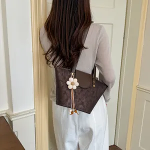 Detail view of the stylish dark brown shoulder tote bag with a cute daisy flower pendant.