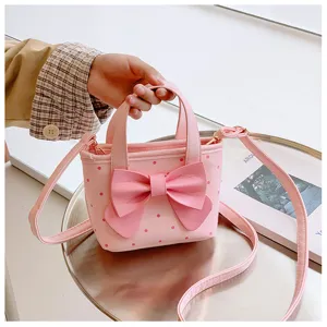 Nahaufnahme einer süßen rosa Kinder Handtasche mit Punkten, großer Schleife und Tragegurt.