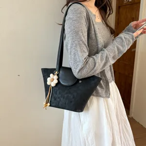 Scene detail of stylish black shoulder tote bag with cute floral charm, perfect daily wear.