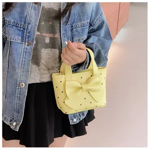 Nahaufnahme der süßen gelben Kinderhandtasche mit Polka-Dots und einer großen Schleife.