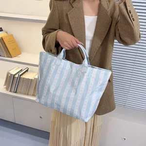 Detailed view of the light blue striped canvas tote bag showing its elegant bow pattern.