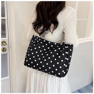 Vue détaillée du sac à bandoulière à pois noirs et blancs avec une élégante bandoulière chaîne.