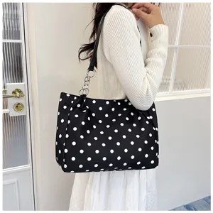 Vue détaillée du sac à épaule chic à pois noirs et blancs avec chaîne en métal.