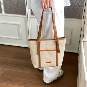 Casual woven canvas tote bag with brown leather handles and front pocket for daily commuting.