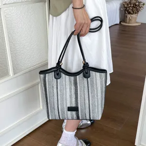 Detailed view of women's black and white woven tote shoulder bag with leather handles.